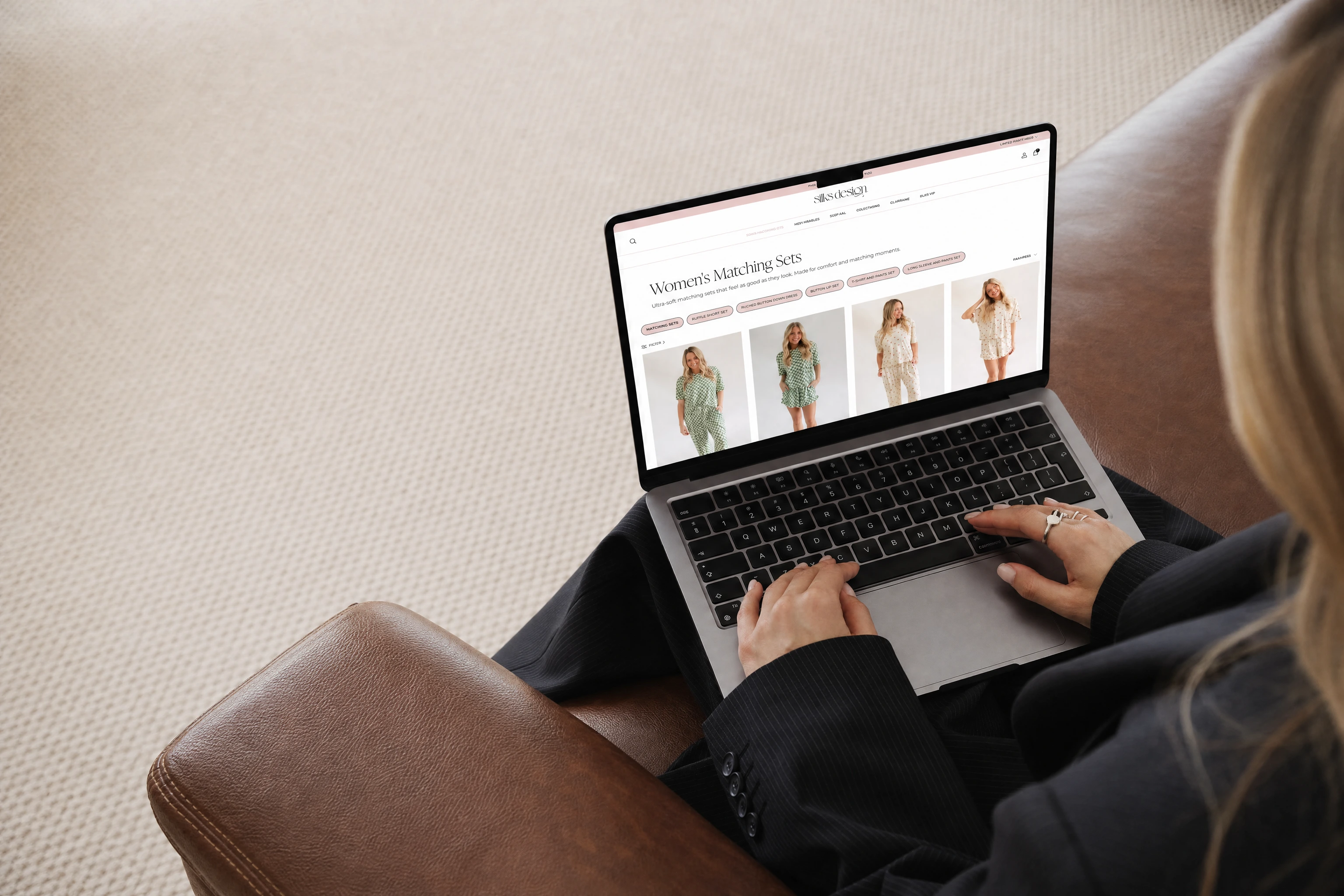 Someone browsing an online clothing store on a laptop at a wooden table